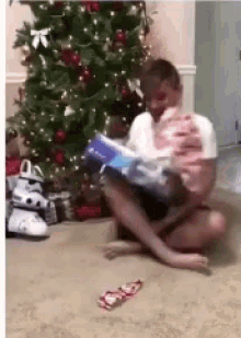 a person is sitting on the floor with a christmas tree in the background