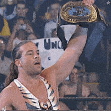 a man in a wrestling ring holds up a championship belt in front of a sign that says unc