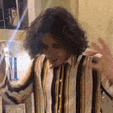 a man with curly hair is wearing a striped shirt and dancing .
