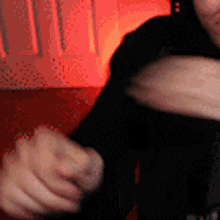 a person 's arm is visible in a blurry photo with a red light behind them