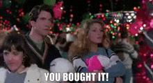 a family is sitting in front of a christmas tree with the words `` you bought it '' written above them .