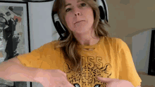 a woman wearing headphones and a yellow shirt with a leopard print on it .