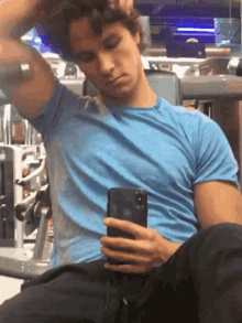 a man in a blue shirt is taking a selfie with his phone