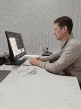 a man sits at a desk in front of a computer monitor that says microsoft on it