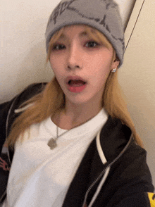 a woman wearing a gray beanie and a white shirt