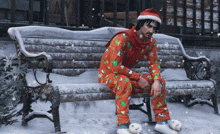a man in a santa hat sits on a snow covered bench