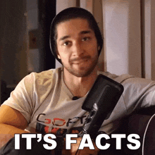 a man sitting in front of a microphone with the words it 's facts above him