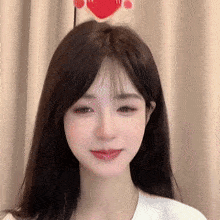 a close up of a woman 's face with a red heart on her forehead .