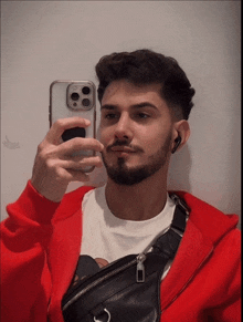 a man in a red jacket is taking a selfie with his iphone