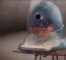 a stuffed dolphin is sitting on a table with a remote control .
