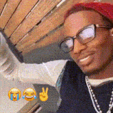 a man wearing glasses and a beanie is smiling and making a peace sign