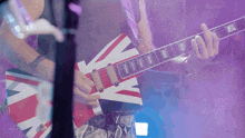 a man playing a red white and blue guitar with a british flag design