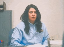 a woman in a blue shirt has a badge on her pocket that says i work for the prison