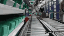 a woman is walking down a conveyor belt in a factory with the website gif-erstellen.com in the lower right corner