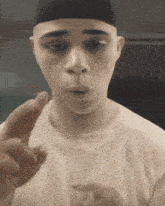 a man wearing a white shirt and a black hat is pointing his finger