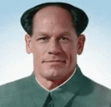 a man with a bald head is wearing a green suit and tie and making a funny face .