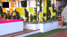 a woman in a bikini leans against a wall in front of a pink couch
