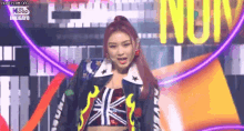 a woman is standing on a stage wearing a crop top and a jacket .
