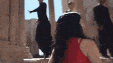 a woman in a red dress is standing in front of a group of people dancing in a building .