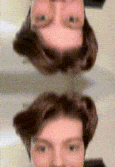 a man is taking a selfie in front of a mirror with his head upside down .