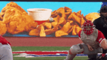a baseball player is getting ready to catch a ball in front of an advertisement for chicken nuggets