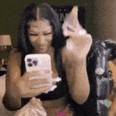 a woman is sitting on a bed looking at her phone and making a face .