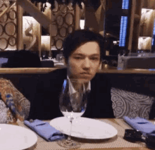 a man is sitting at a table with a glass of wine and plates .