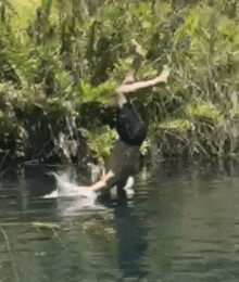 a man is jumping into a body of water .