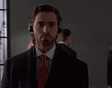 a man in a suit and tie wearing headphones looks at the camera