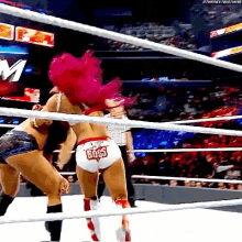 two women are wrestling in a ring and one of them has the word boss on her shorts .