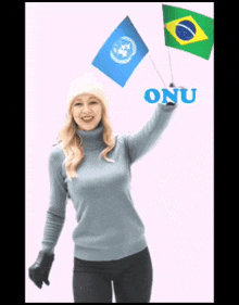 a woman in a blue sweater holds up two small flags with the word onu written in blue