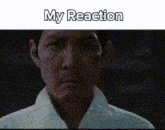 a man in a white shirt is looking at the camera with the words `` my reaction '' written on the bottom .