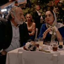 a man and a woman sit at a table with glasses of tea