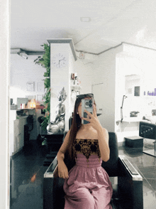 a woman taking a picture of herself in a mirror with a clock behind her