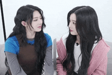 two women are sitting next to each other on a couch and looking at each other