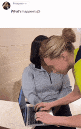 two women are looking at a laptop with the caption " what 's happening " on the bottom