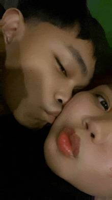 a close up of a man kissing a woman on the cheek with her eyes closed