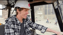 a man wearing a hard hat and plaid shirt is smiling