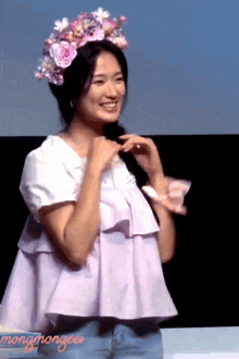 a woman wearing a flower crown stands in front of a screen that says mongmongeer