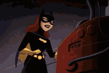 a woman in a batman costume is standing in front of a red door .