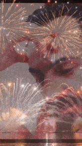 a man and woman are kissing in front of a fireworks display .