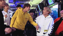 a man in a yellow hoodie talks to another man in a white sweater