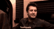 a man is smiling and pointing at the camera while saying toothpaste .