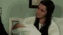 a woman holds a baby in her arms in a hospital bed