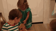 a little girl in a green dress petting a puppy