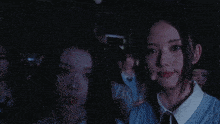 a group of people are standing in a dark room with a man covering his face with his hand