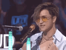 a man wearing sunglasses is singing into a microphone on a stage .