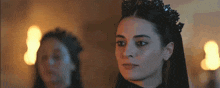 a woman with a crown on her head looks at the camera .