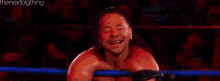 a wrestler is laying on the ground in a wrestling ring while another wrestler stands over him .