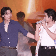 a man singing into a microphone while another man stands behind him